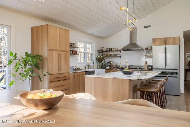 a kitchen with stainless steel appliances kitchen island granite countertop a table chairs stove and refrigerator