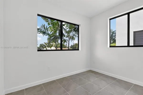 an empty room with windows and painting on the wall