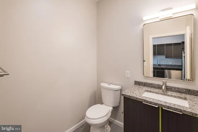 a bathroom with a granite countertop toilet and a sink