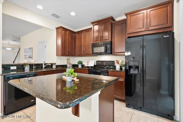 a kitchen with stainless steel appliances granite countertop a refrigerator a stove and a sink with wooden cabinets