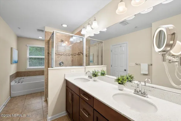 a bathroom with a double vanity sink a mirror and a bathtub