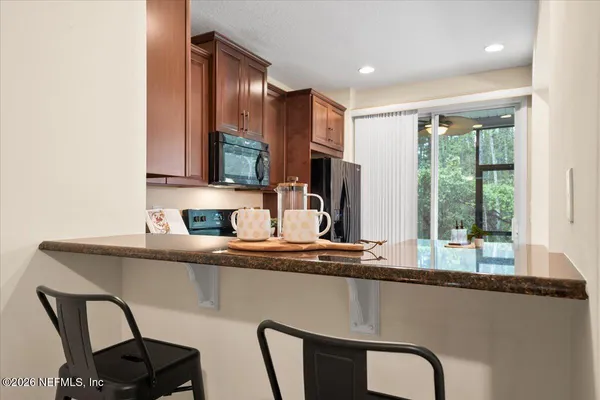 a kitchen with stainless steel appliances granite countertop a table chairs in it and wooden floors