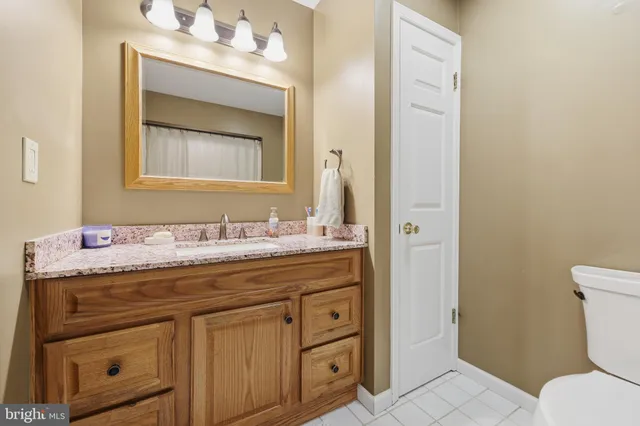 a bathroom with a granite countertop toilet sink and mirror
