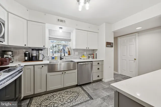 a kitchen with white cabinets appliances and a sink