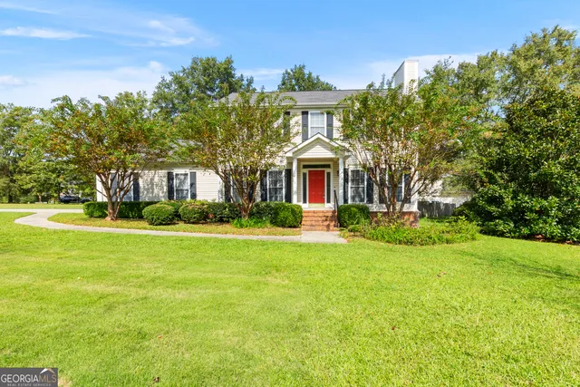 a front view of a house with yard and green space