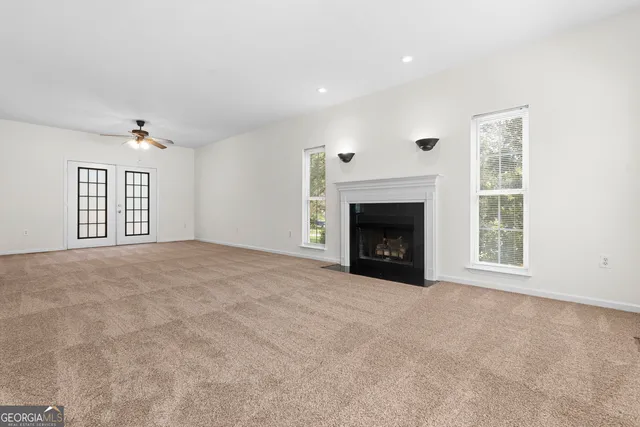 a view of an empty room with a window and a kitchen