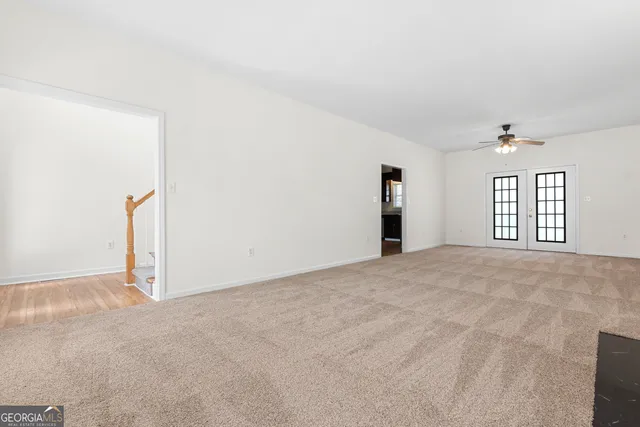 an empty room with windows and ceiling fan