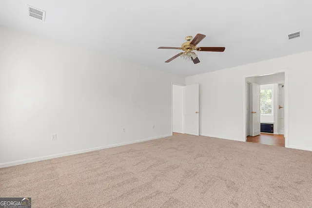 an empty room with windows and fan