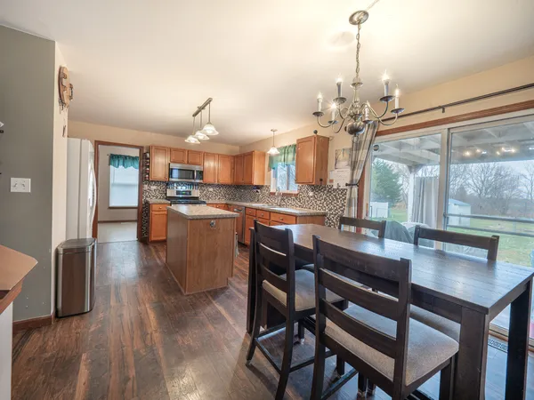 a view of a dining room and livingroom with furniture wooden floor a chandelier