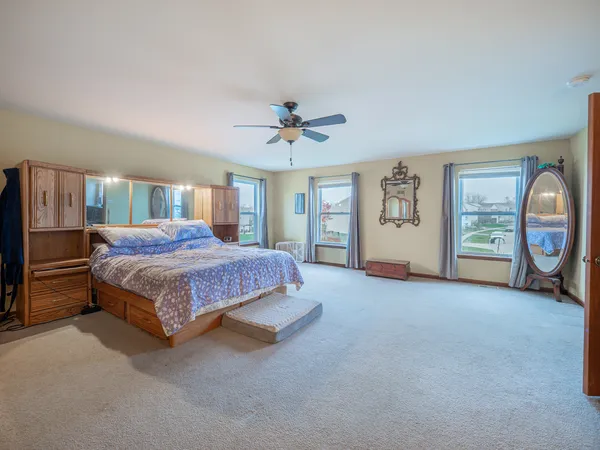 a spacious bedroom with a large bed a chandelier and windows