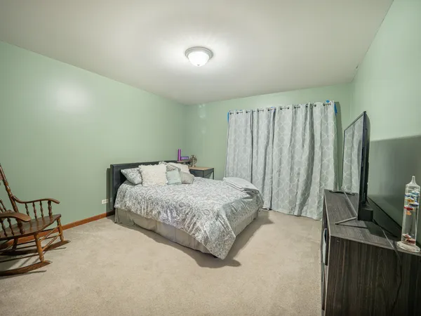 a spacious bedroom with a bed table and a flat screen tv
