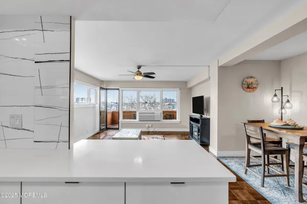 a kitchen with stainless steel appliances a sink dishwasher a stove top oven a refrigerator with white cabinets and a wooden floor