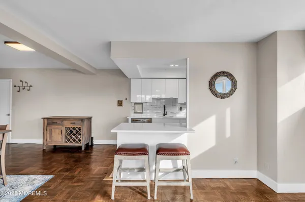 a living room with stainless steel appliances furniture a rug and a kitchen view