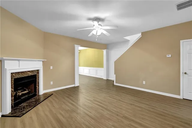 a view of an empty room with wooden floor fireplace and a window