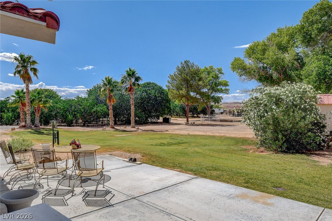 1950 Bowman Road Logandale, NV 89021 - Photo 51 of 81 A spacious backyard with mature trees, verdant grass, and a concrete patio ideal for outdoor gatherings.