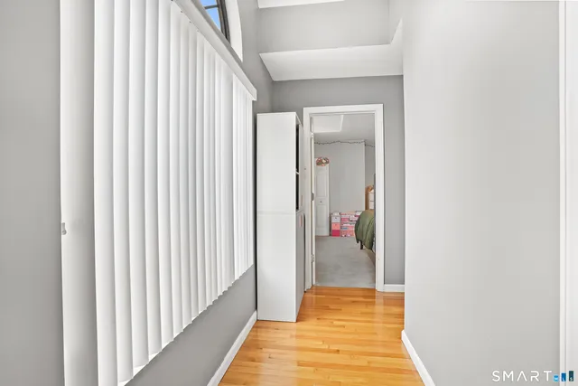 a view of a hallway with wooden floor and closet