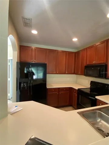 a kitchen with granite countertop a refrigerator a sink and wooden cabinets