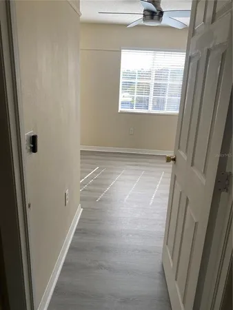 a view of an empty room with wooden floor and a window