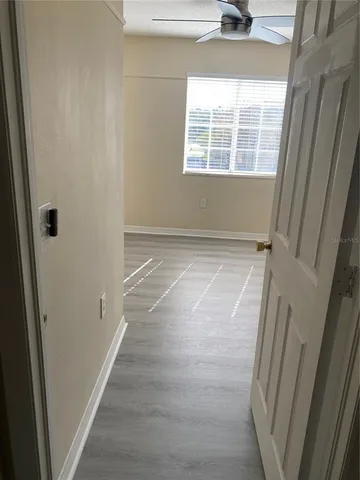 a view of an empty room with wooden floor and a window