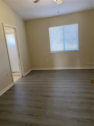 a view of an empty room with wooden floor and a window
