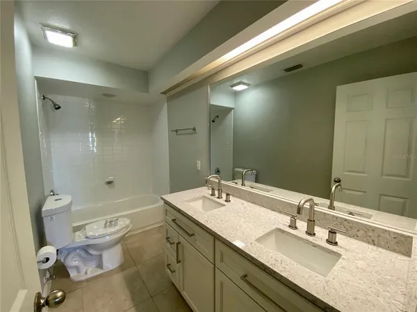 a bathroom with a granite countertop double vanity sink toilet and shower