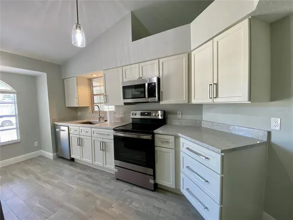 a kitchen with granite countertop a stove sink and microwave