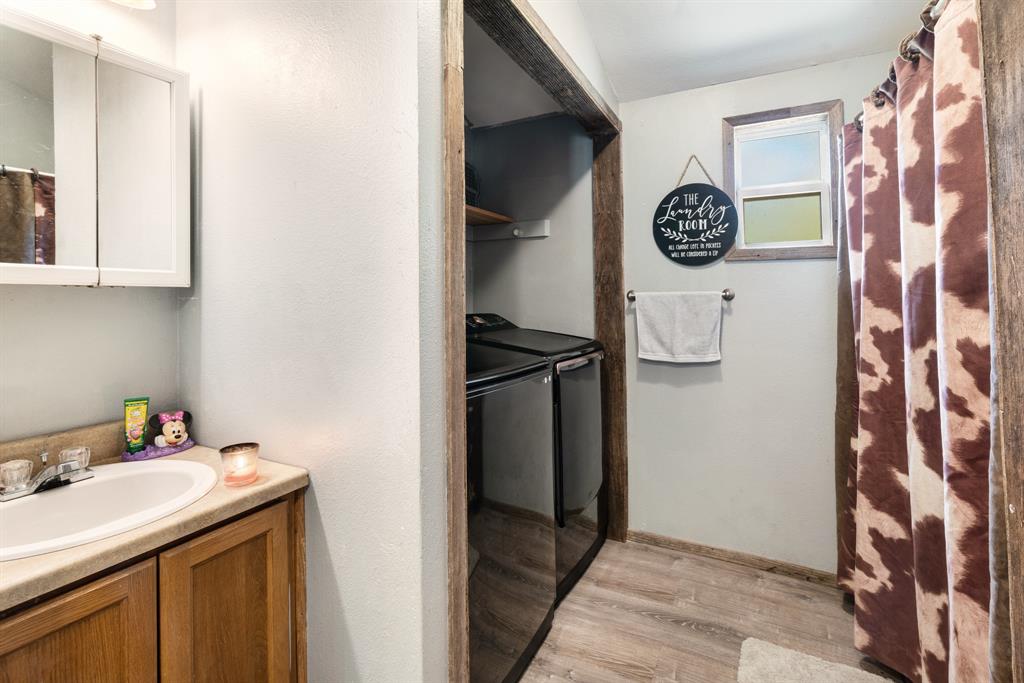 28 Private Road Sumner, TX 75486 - Photo 11 of 17 Bathroom featuring light wood-style floors, vanity, washer and clothes dryer, and a shower with curtain