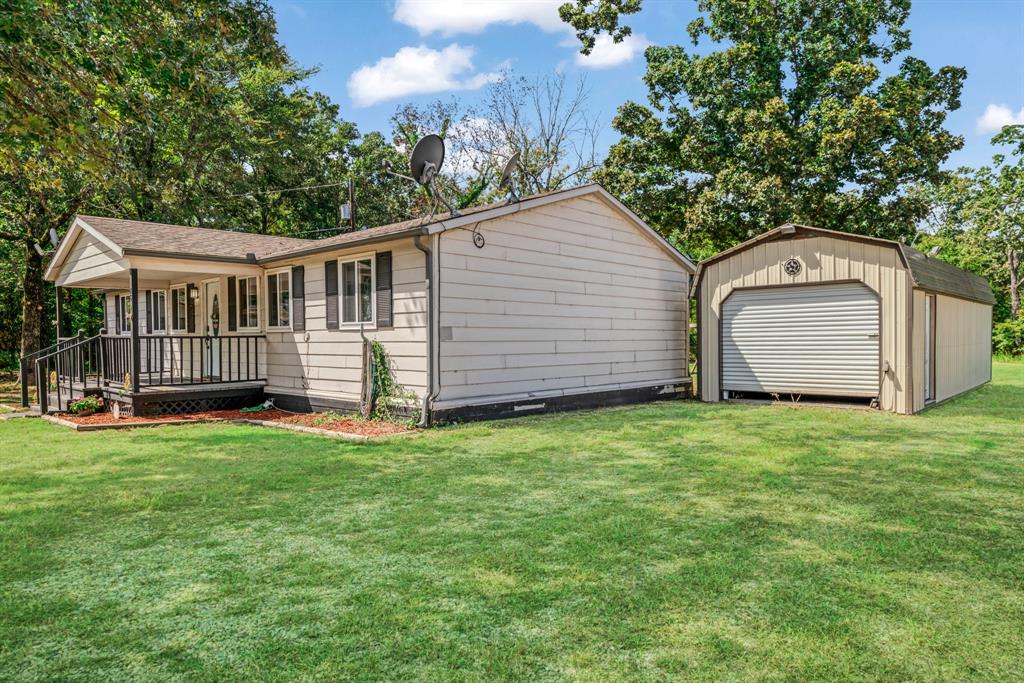 28 Private Road Sumner, TX 75486 - Photo 2 of 17 View of home's exterior featuring a lawn, an outbuilding, covered porch, and a shingled roof