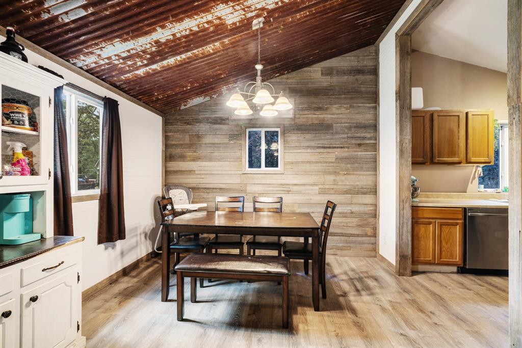 28 Private Road Sumner, TX 75486 - Photo 5 of 17 Dining room with wood walls, healthy amount of natural light, vaulted ceiling, light wood-type flooring, and a chandelier