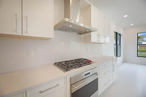a kitchen with granite countertop a stove and a white cabinets