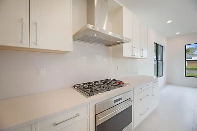a kitchen with granite countertop a stove and a white cabinets