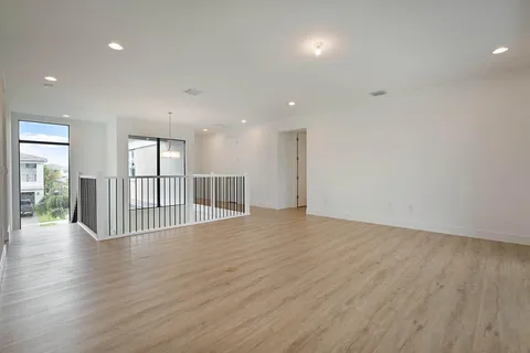 a view of an empty room with wooden floor and windows