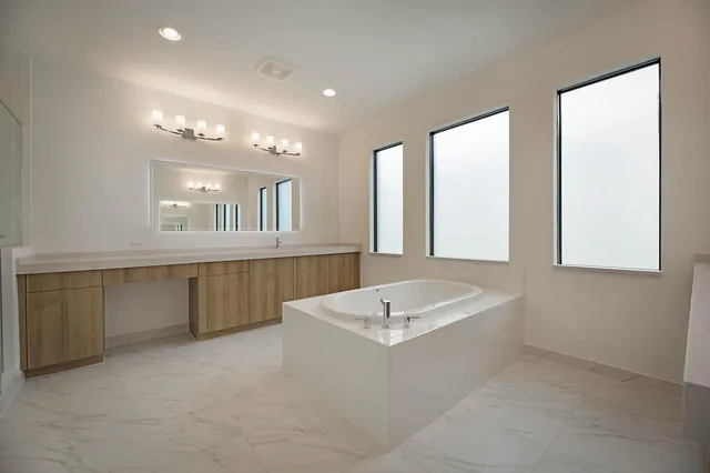 a spacious bathroom with a tub a sink and mirror