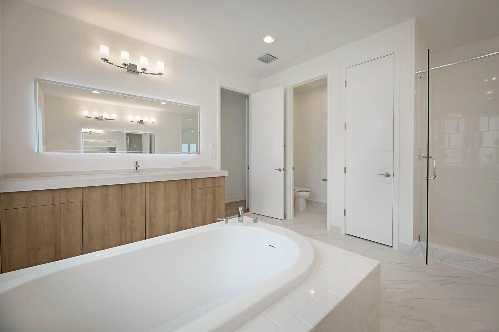 17062 Watersprite Lakes Road Boca Raton, FL 33496 - Photo 28 of 42 a spacious bathroom with a bathtub a shower a sink and a mirror