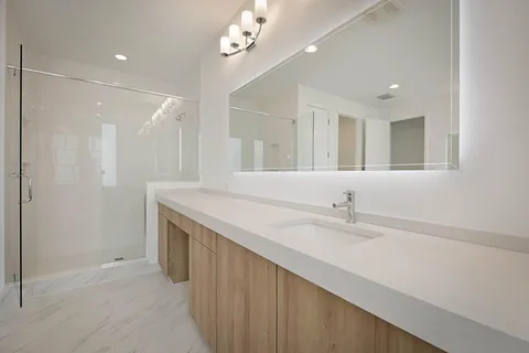 a bathroom with a sink a large mirror and a shower