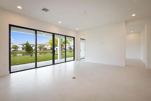 a view of an empty room with wooden floor and floor to ceiling window