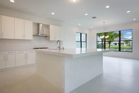 a kitchen with stainless steel appliances granite countertop a sink and white cabinets with wooden floor