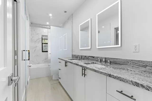 a bathroom with a granite countertop sink mirror and a bathtub