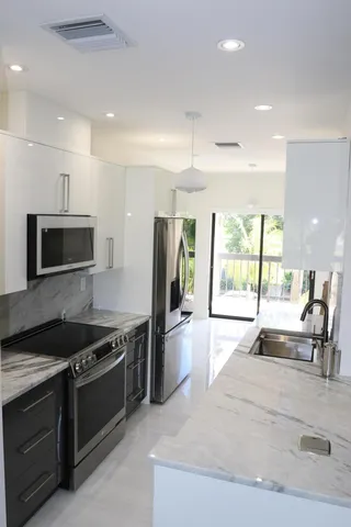 a kitchen with stainless steel appliances granite countertop a sink and wooden cabinets