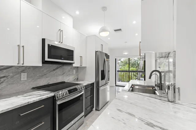 a kitchen with stainless steel appliances kitchen island granite countertop a stove and a sink with granite countertops