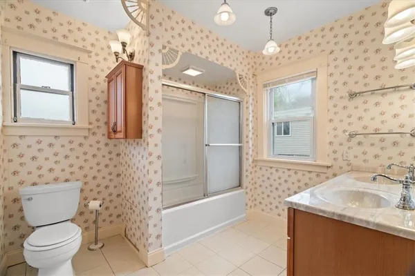 a bathroom with a granite countertop sink a toilet a mirror and shower