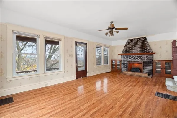 an empty room with windows fireplace and wooden floor
