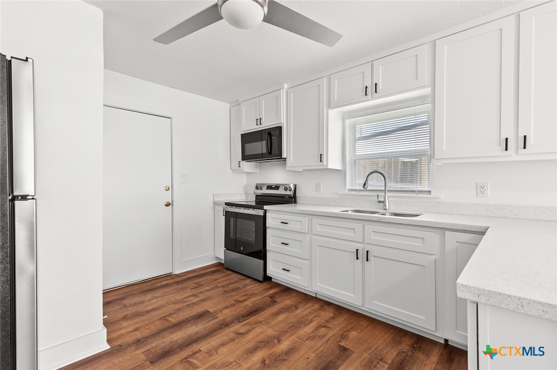 1020 South 23rd Street Temple, TX 76504 - Photo 12 of 38 a kitchen with a sink cabinets and wooden floor