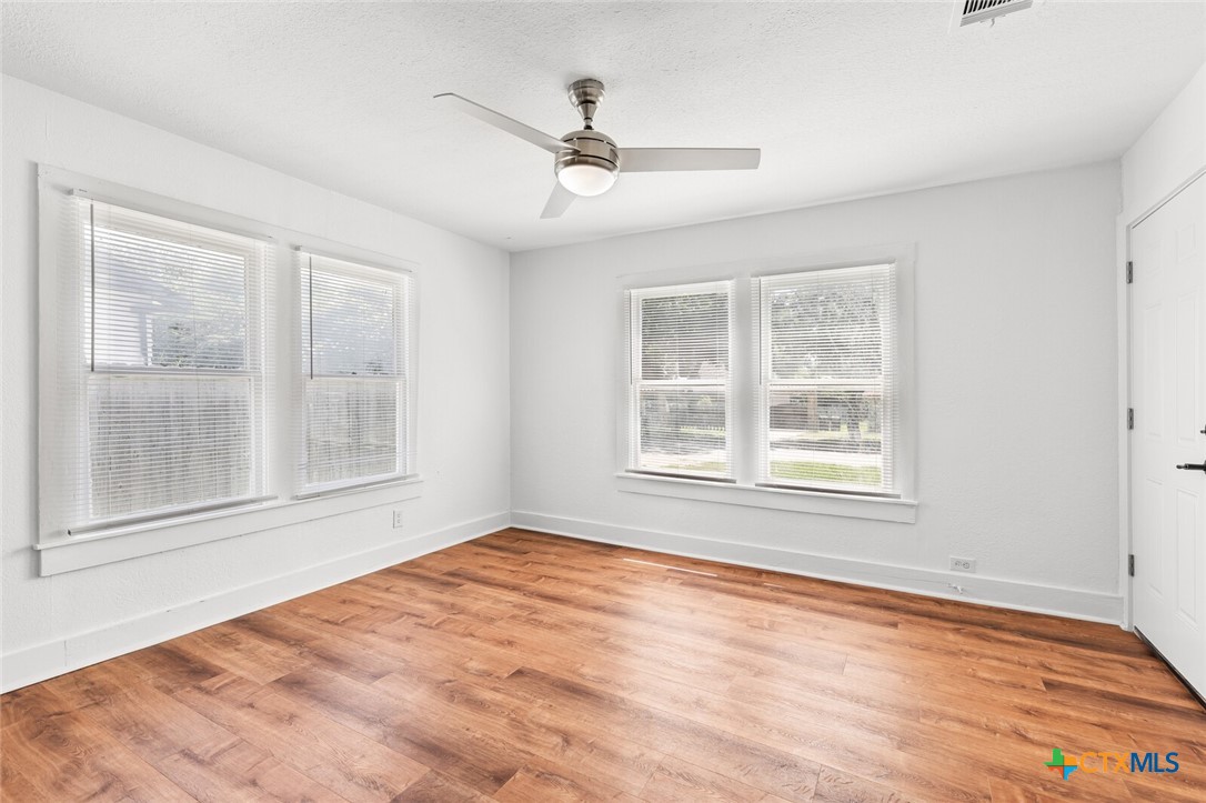 1020 South 23rd Street Temple, TX 76504 - Photo 17 of 38 an empty room with wooden floor ceiling fan and windows