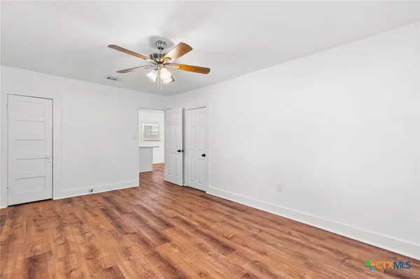 a view of a room with a ceiling fan and wooden floor