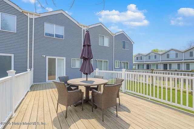 a view of a house with a wooden deck and furniture