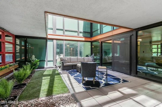 a view of a patio with table and chairs potted plants and floor to ceiling window
