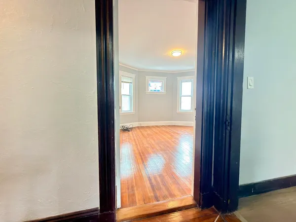 an empty room with wooden floor and windows