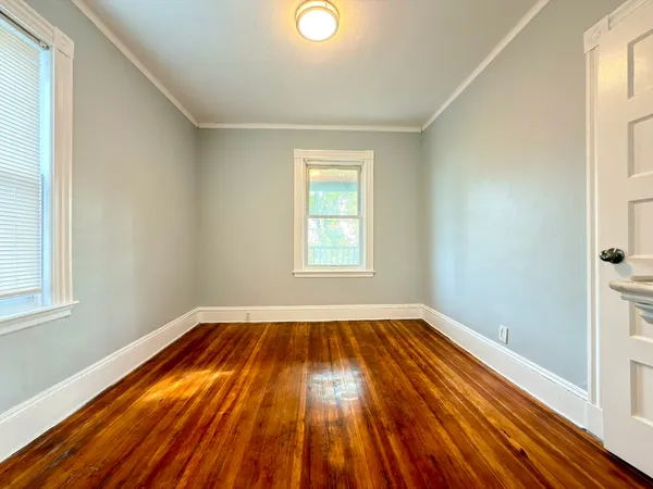 a view of empty room with wooden floor and kitchen