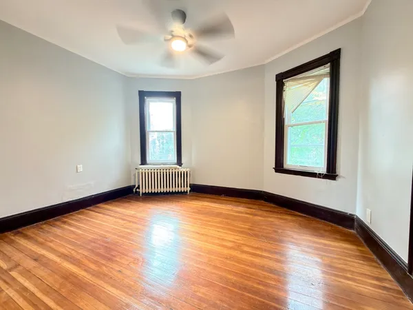 a view of empty room with wooden floor and fan